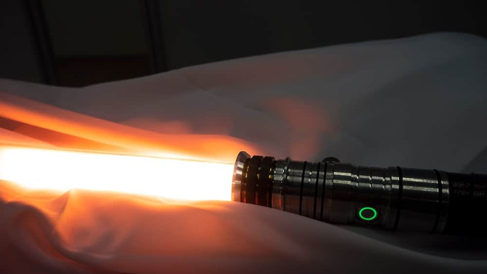 an orange lightsaber on a white cloth in Star Wars