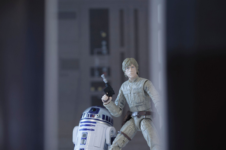 Luke Skywalker holding a blaster and going with astromech droid R2D2
