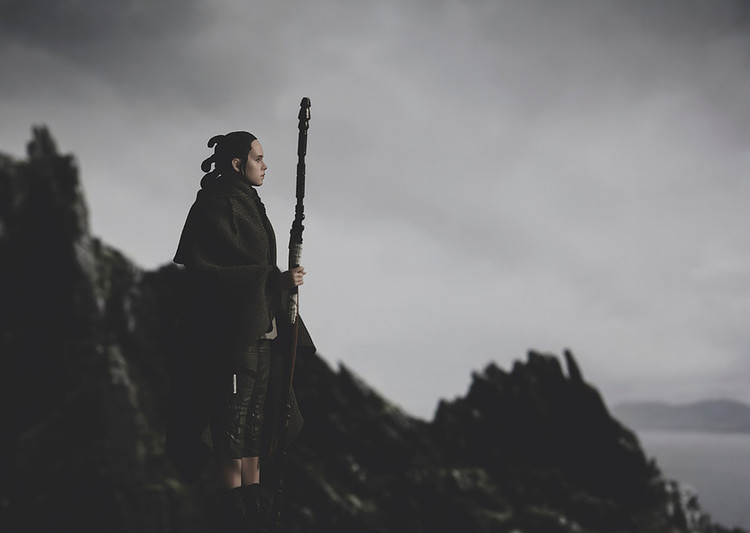 Rey holding her quarterstaff arrives on Ahch-To