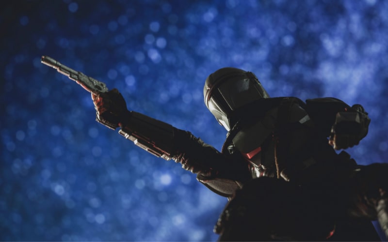 bounty hunter Din Djarin heading his blaster to the starry sky